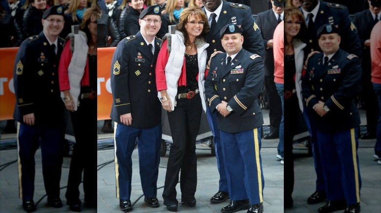 Sarah Palin sonríe con dos agentes mientras lleva un chaleco acolchado