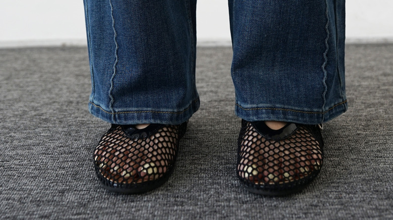 Mujer en jeans con zapatos sintéticos de malla