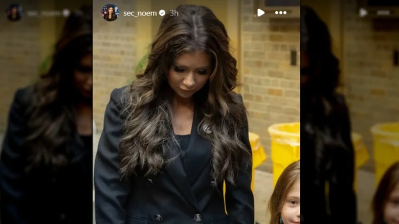 Kristi Noem mirando hacia abajo mostrando su mala aplicación de extensiones de cabello