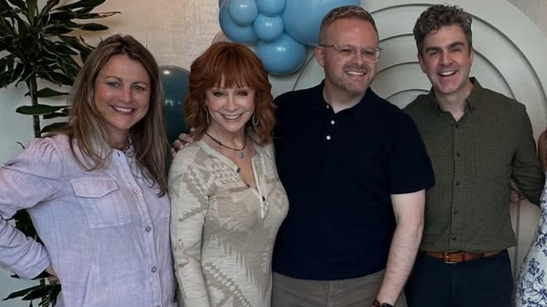 Reba McEntire sonriendo mientras posa con amigos en un evento
