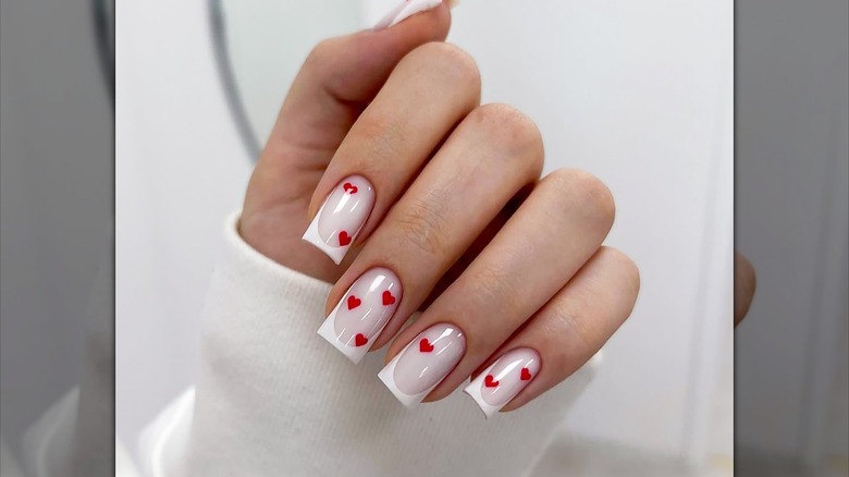 Arte de uñas con pequeños corazones rojos.
