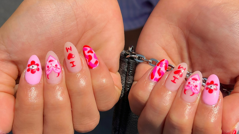 Arte de uñas con corazones, puntos e iniciales.