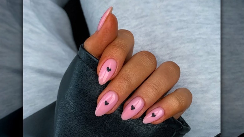 Arte de uñas con pequeños corazones negros.