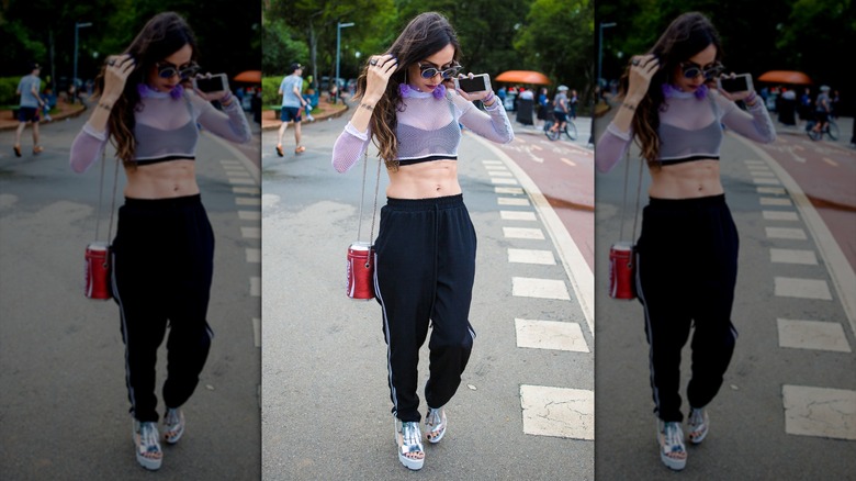 Una mujer vestida con un top corto y pantalones deportivos.