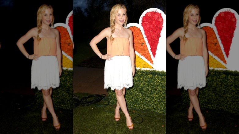Tara Lipinski con falda blanca y top naranja sin tirantes