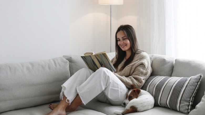 Una mujer lee en el sofá con su perro