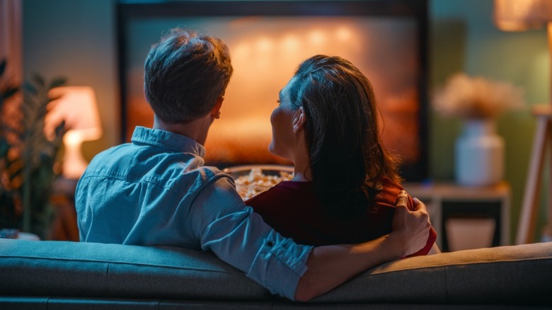Una pareja mira televisión en el sofá.