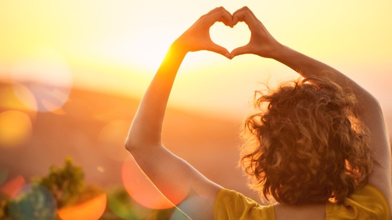 Una mujer levanta las manos en forma de corazón.