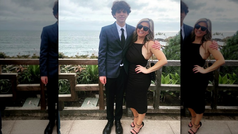 Brandi Passante luciendo un vestido negro y parada junto a su hijo frente al mar
