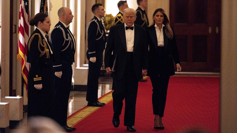 Melania Trump vistiendo un traje blanco y negro junto a su esposo, el presidente Donald Trump, en la Cena de Gobernadores de 2025.