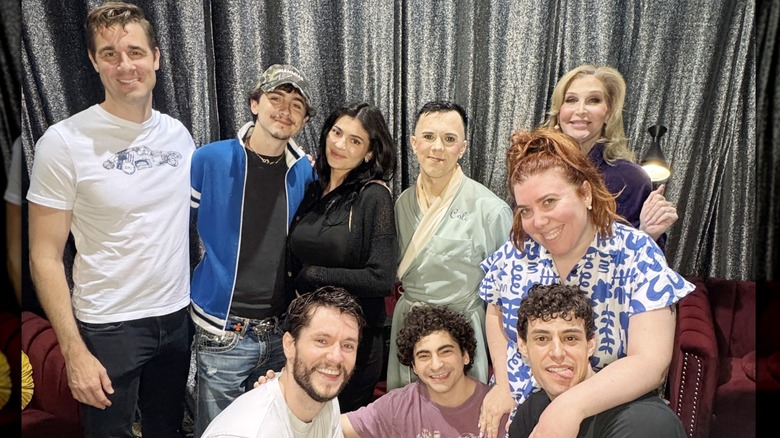 Timothée Chalamet y Kylie Jenner posando detrás del escenario con artistas de Broadway