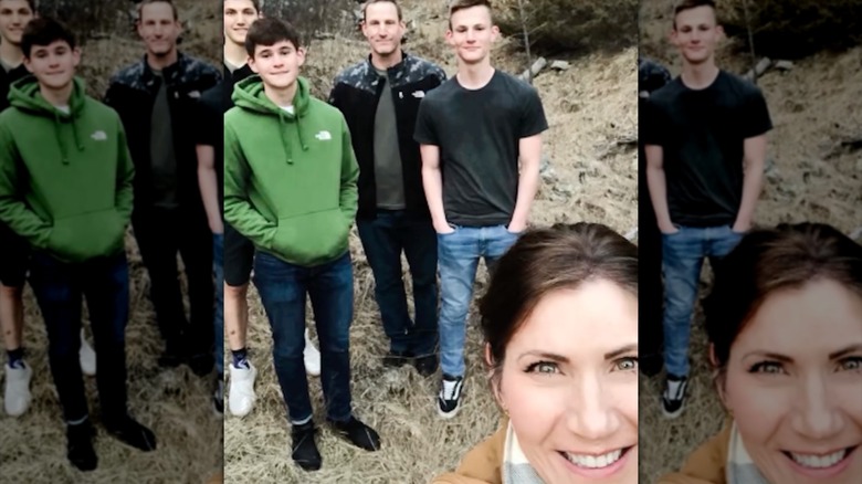Kristi Noem tomándose una selfie al aire libre con poco maquillaje