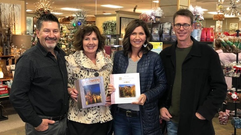 Kristi Noem sosteniendo un libro en una tienda y usando poco maquillaje