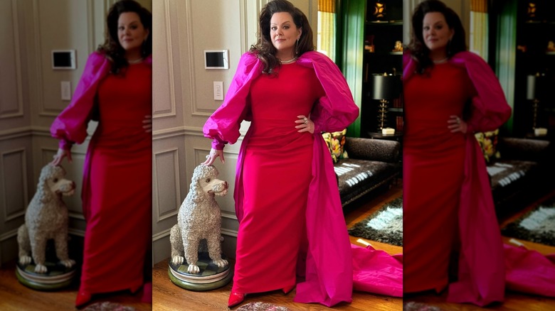 Melissa McCarthy posa con un vestido y su mano sobre una estatua de perro cercana