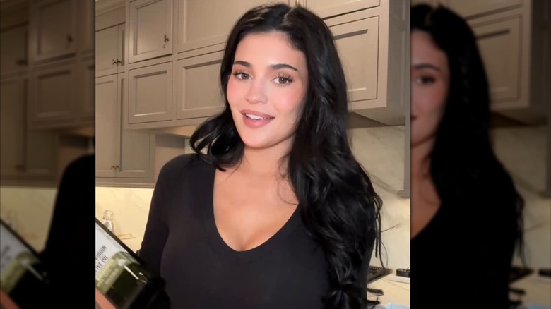 Kylie Jenner con un look sin maquillaje sosteniendo una botella de Smash Oil