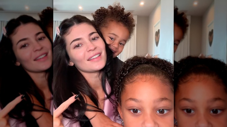 Kylie Jenner con maquillaje ligero posando con sus dos hijos Stormi y Aire Webster