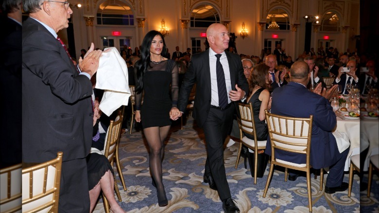 La imagen completa de Lauren Sanchez y Jeff Bezos. Sánchez lleva un minivestido negro con mangas transparentes.