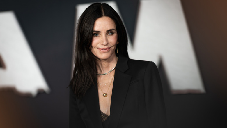 Courteney Cox sonriendo con una chaqueta negra