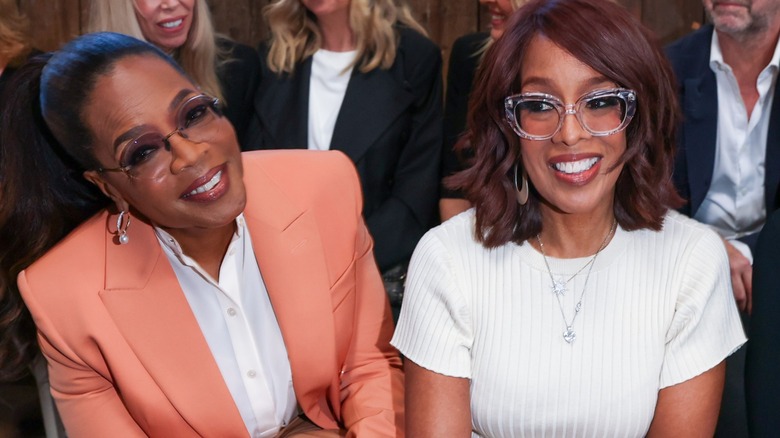 Oprah Winfrey y Gayle King sentadas juntas en un desfile de moda