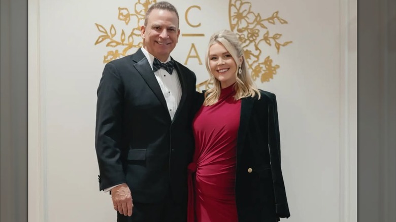 Karoline Leavitt con un vestido color vino posando junto a Nicholas Riccio, que parece mucho mayor que ella con traje.