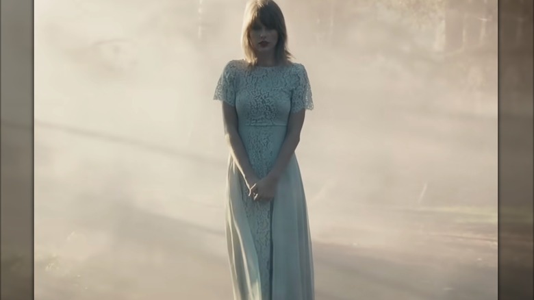 Taylor Swift está sola con un vestido largo azul pálido con mangas cortas de encaje.