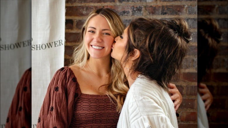 Kristi Noem besa a su hija Kennedy en la mejilla frente a una pared de ladrillos en su baby shower