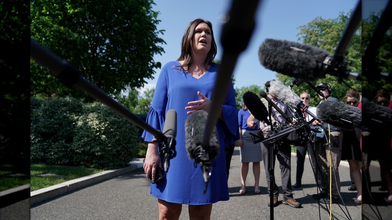 Sarah Huckabee Sanders habla con los periodistas con un vestido recto azul con mangas acampanadas
