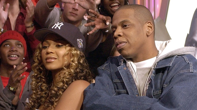 Una imagen retrospectiva de Jay-Z y Beyonce. Ambos son entre 15 y 20 años más jóvenes y posan hombro con hombro con los brazos cruzados.
