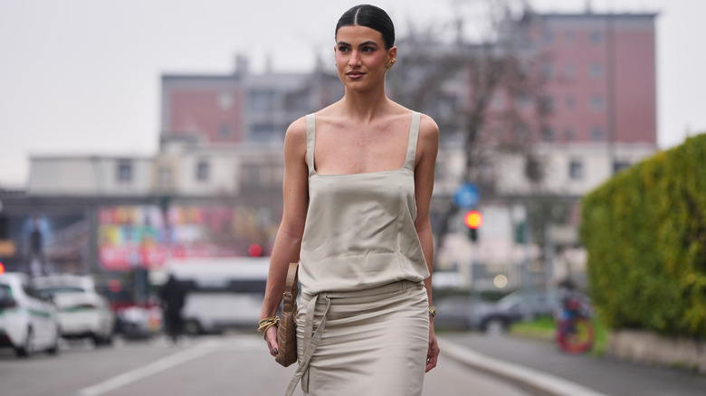 Una mujer que llevaba un vestido beige aburrido inclinado minimalista