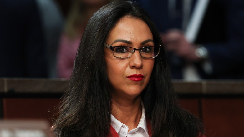 Lauren Boebert en una audiencia. Es una mujer de cabello oscuro y bronceado en spray. Lleva gafas de montura oscura y lápiz labial rojo.
