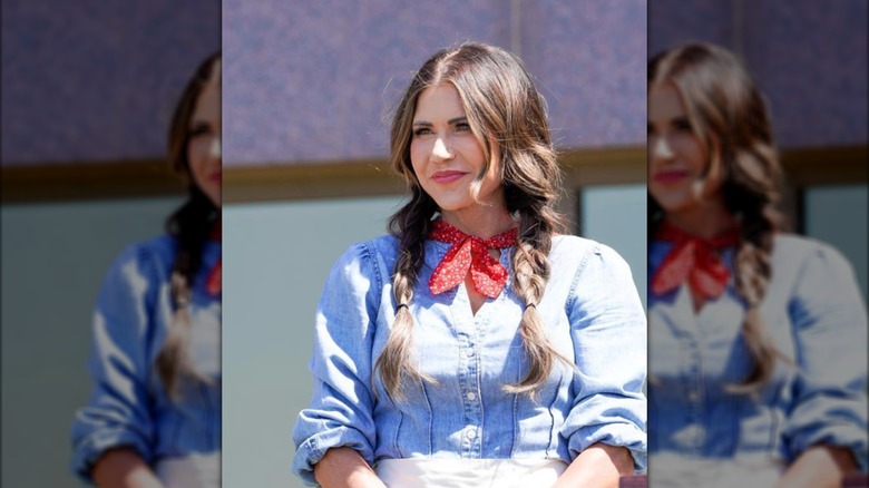 Kristi Noem se encuentra afuera de un edificio con atuendo sureño.