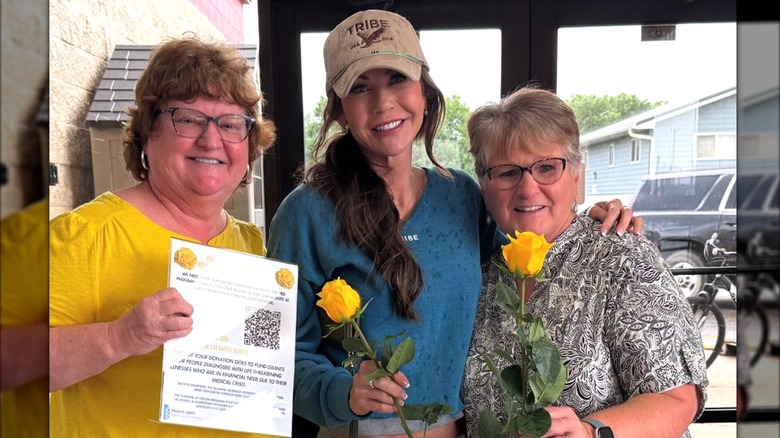 Kristi Noem está flanqueada por dos amigas mientras está en una floristería