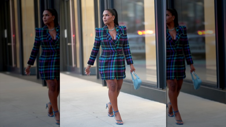Una mujer con un abrigo a cuadros y zapatos azules con un bolso azul.
