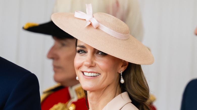 Kate Middleton sonríe mientras usa sombrero para el sol y aretes de perlas
