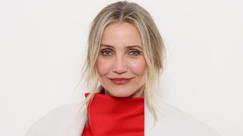 El actor Cameron Diaz con bata blanca y vestido rojo de cuello alto.