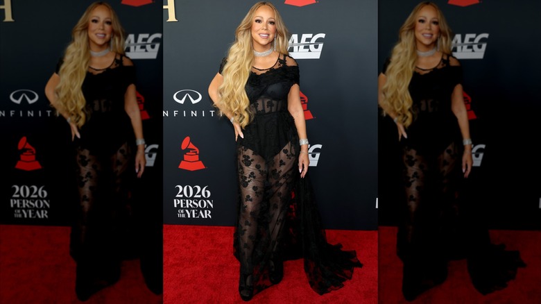 Mariah Carey en la alfombra roja de la Persona del Año de MusiCares 2026. Lleva un vestido largo negro transparente, con apliques florales y un corpiño negro.
