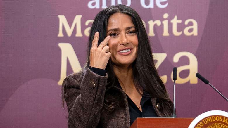 Salma Hayek hablando en un podio mostrando sus grises