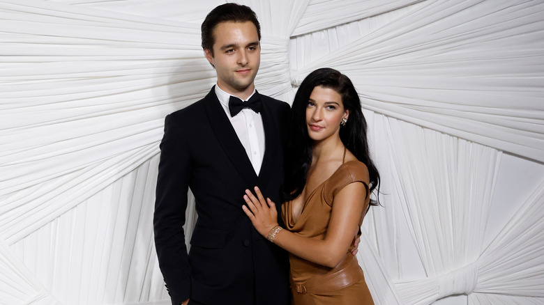 Phoebe Gates con un vestido marrón posando junto a su exnovio Arthur Donald vistiendo un esmoquin