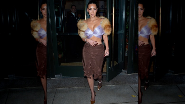 Kim Kardashian es fotografiada con un top lila con adornos de piel y una falda marrón en la ciudad de Nueva York en 2025.