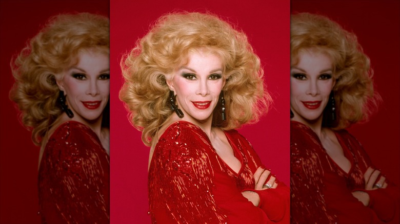 Joan Rivers sonríe con un vestido rojo brillante y lápiz labial rojo.