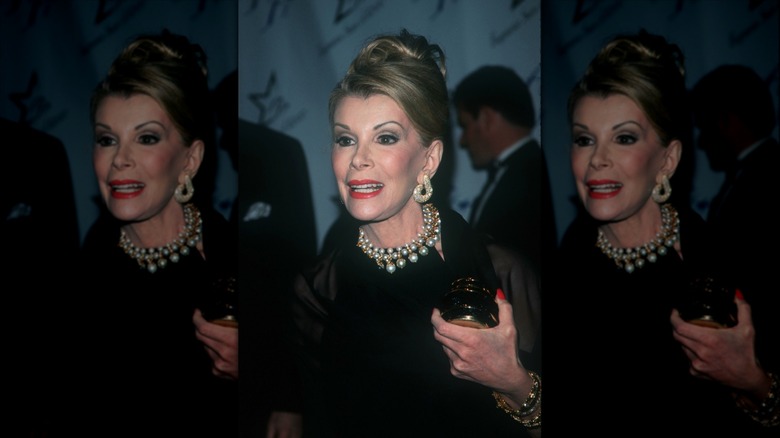 Joan Rivers fotografiada en un evento de alfombra roja con un recogido y perlas.