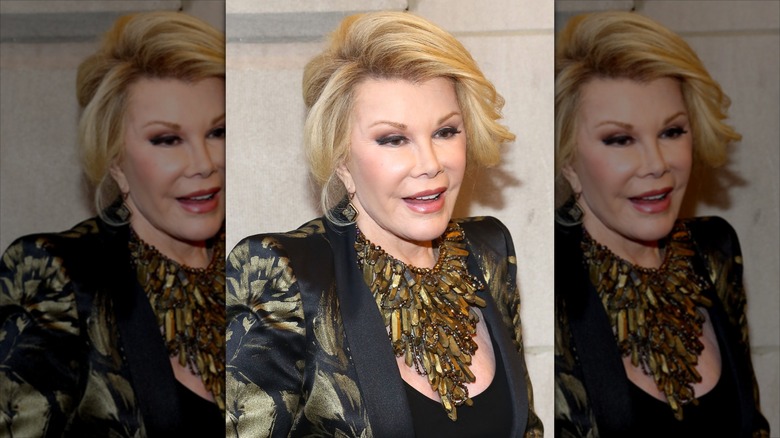 Joan Rivers sonríe con un grueso collar dorado y una chaqueta negra adornada.