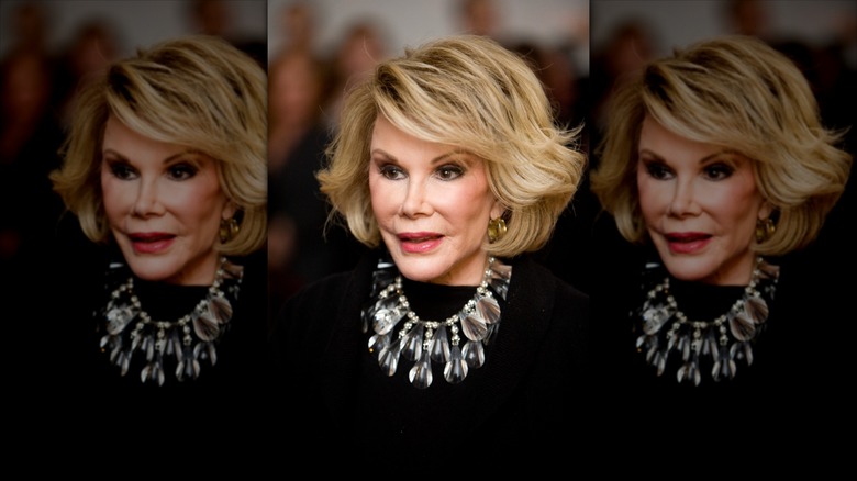 Joan Rivers posa con un llamativo collar plateado sobre un top negro.