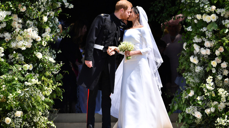 Meghan Markle con su vestido de novia y el príncipe Harry dándose un beso el día de su boda
