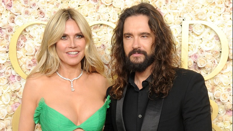 Heidi Klum con un vestido verde y posando con su marido Tom Kaulitz en un evento de alfombra roja.