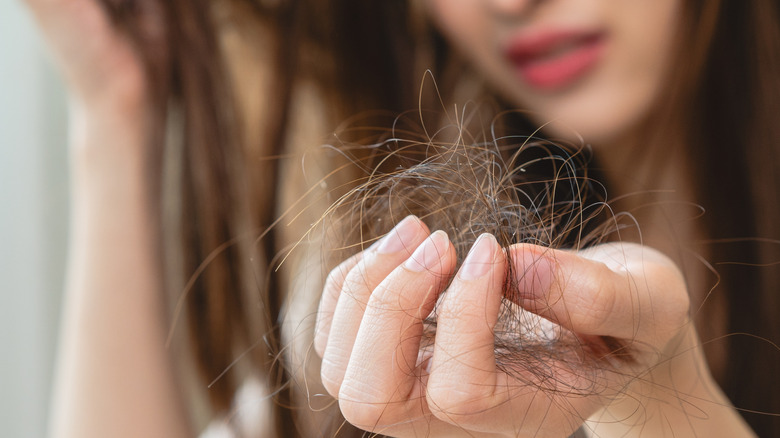 Mujer sosteniendo el cabello caído en la mano