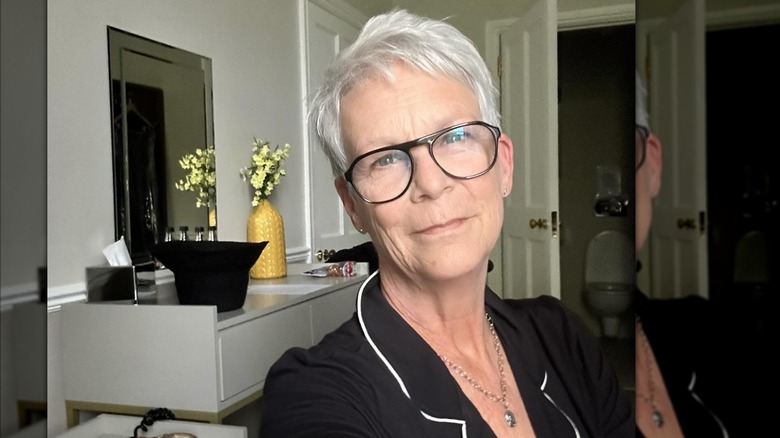 Jamie Lee Curtis con pijama negro y gafas negras en una selfie.