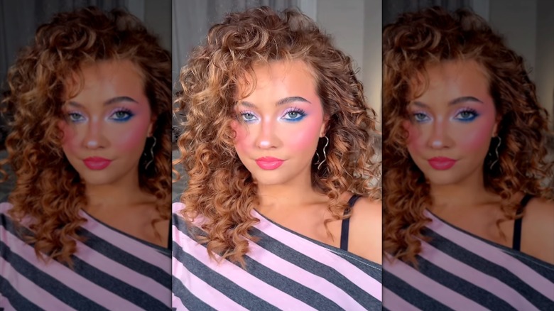 Una mujer con cabello y maquillaje de los 80 tomándose una selfie