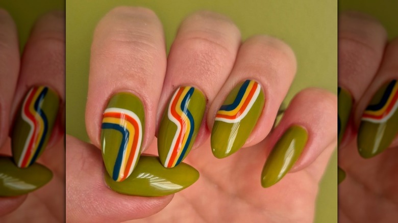 Primer plano de una manicura verde oliva con rayas blancas, rojas, amarillas y azules.
