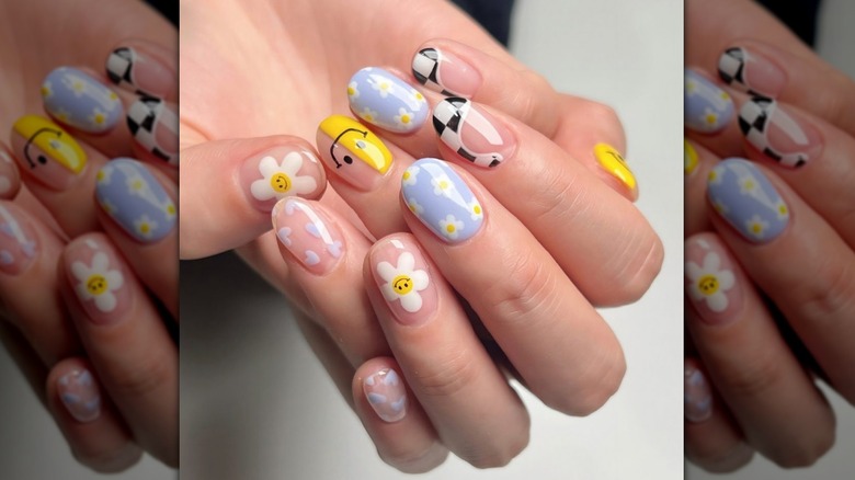 Imagen de cerca de una manicura con flores, caras sonrientes y remolinos.